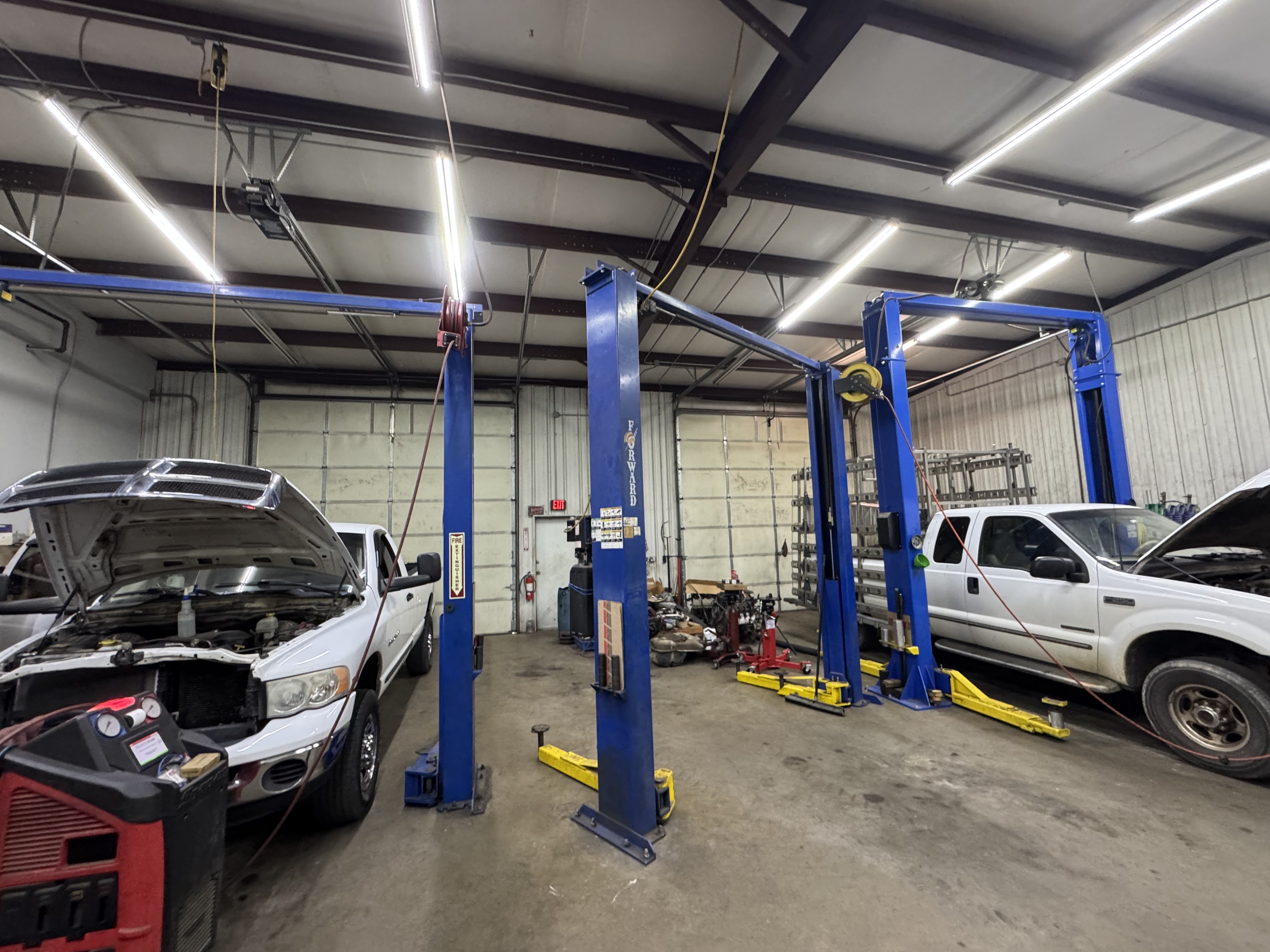 Full-service auto repair shop with work trucks in service bays for mechanical repair and diagnostics