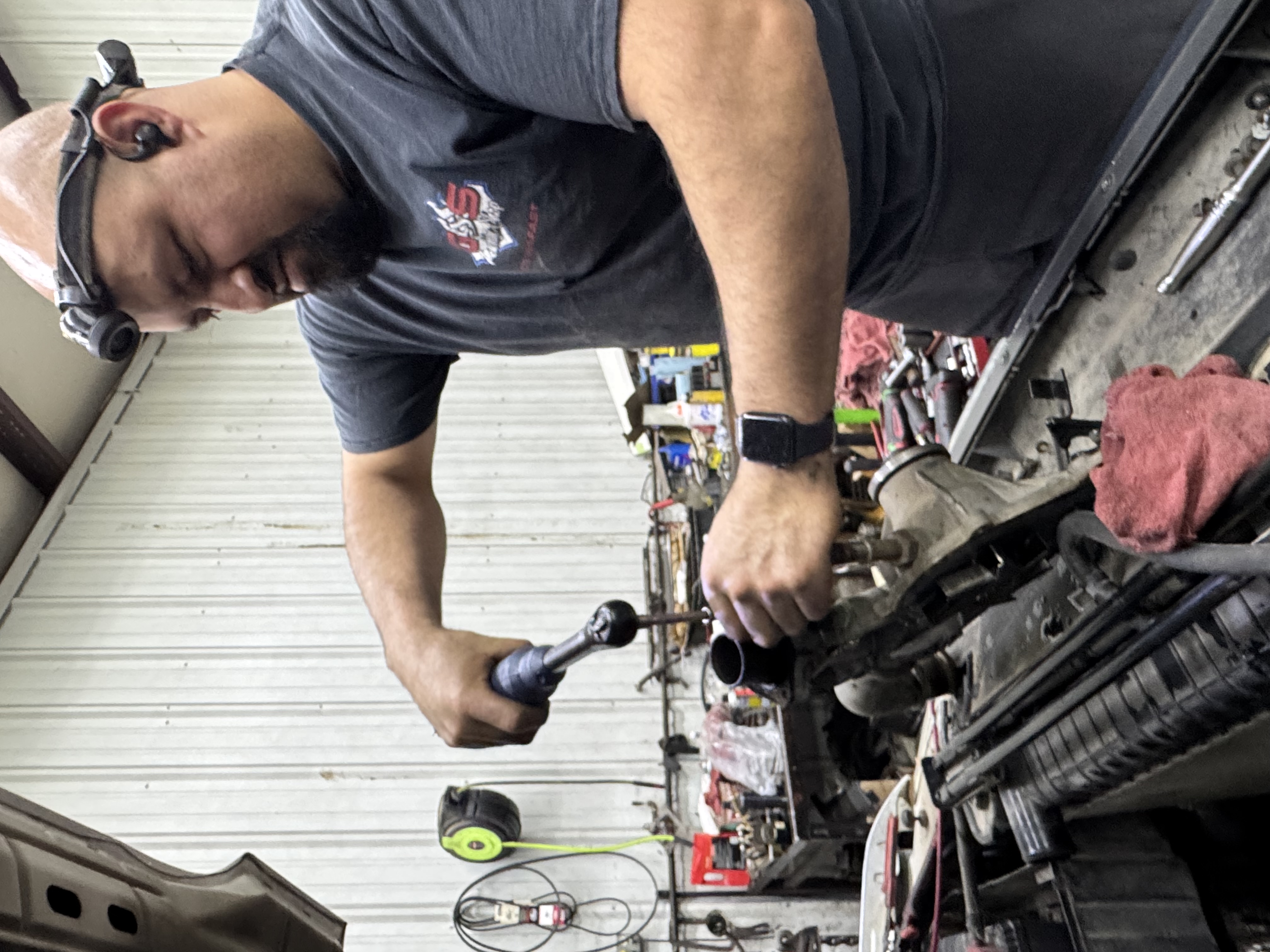Technician removing thermostat housing during engine repair